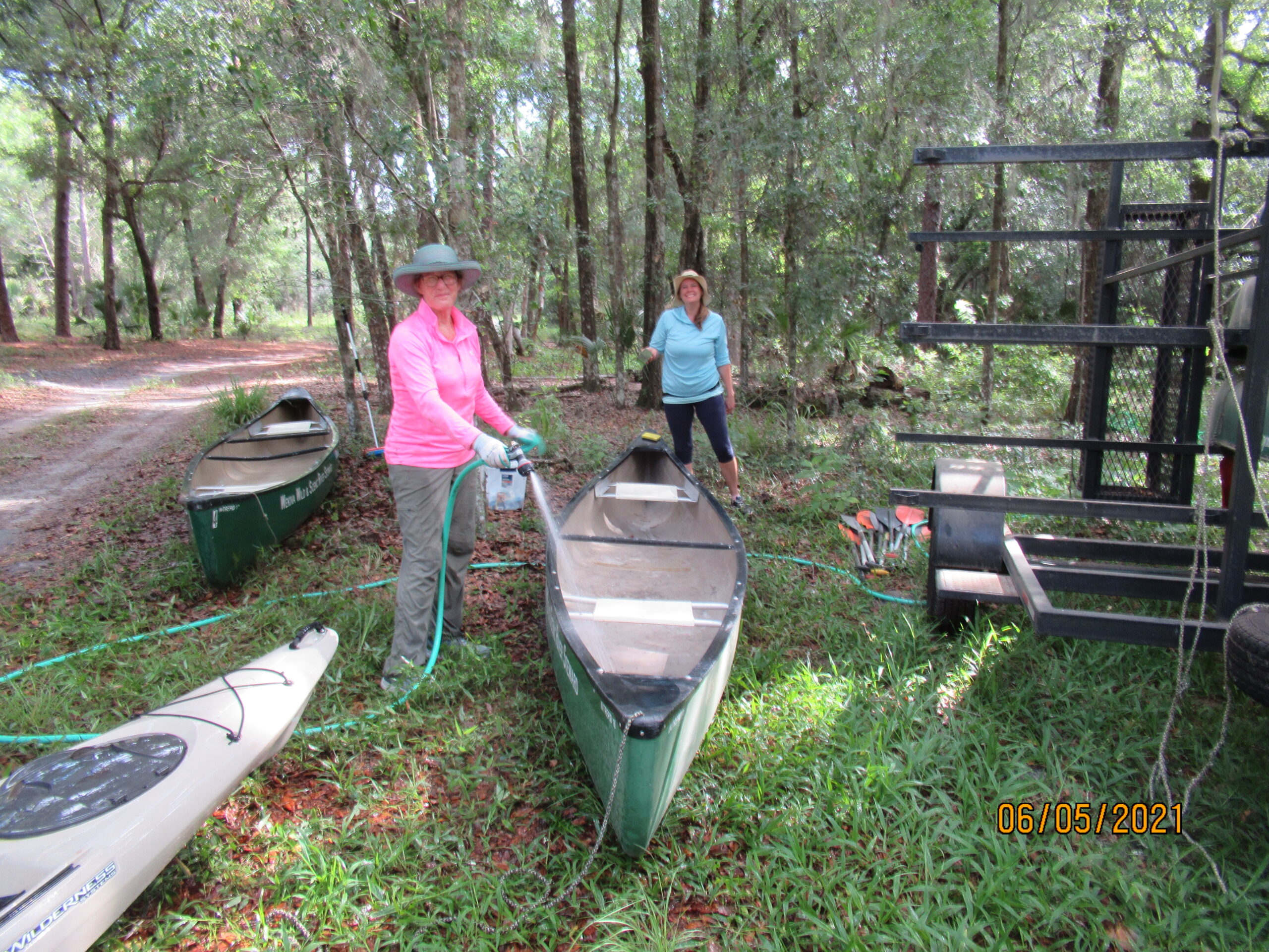 Two people stand next to a canoe they are cleaning