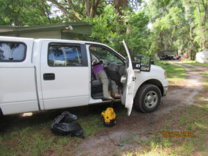A volunteers legs are visible hanging out the side of a F150 as they clean.